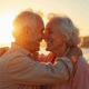 Couple senior souriant sur la plage au lever du soleil